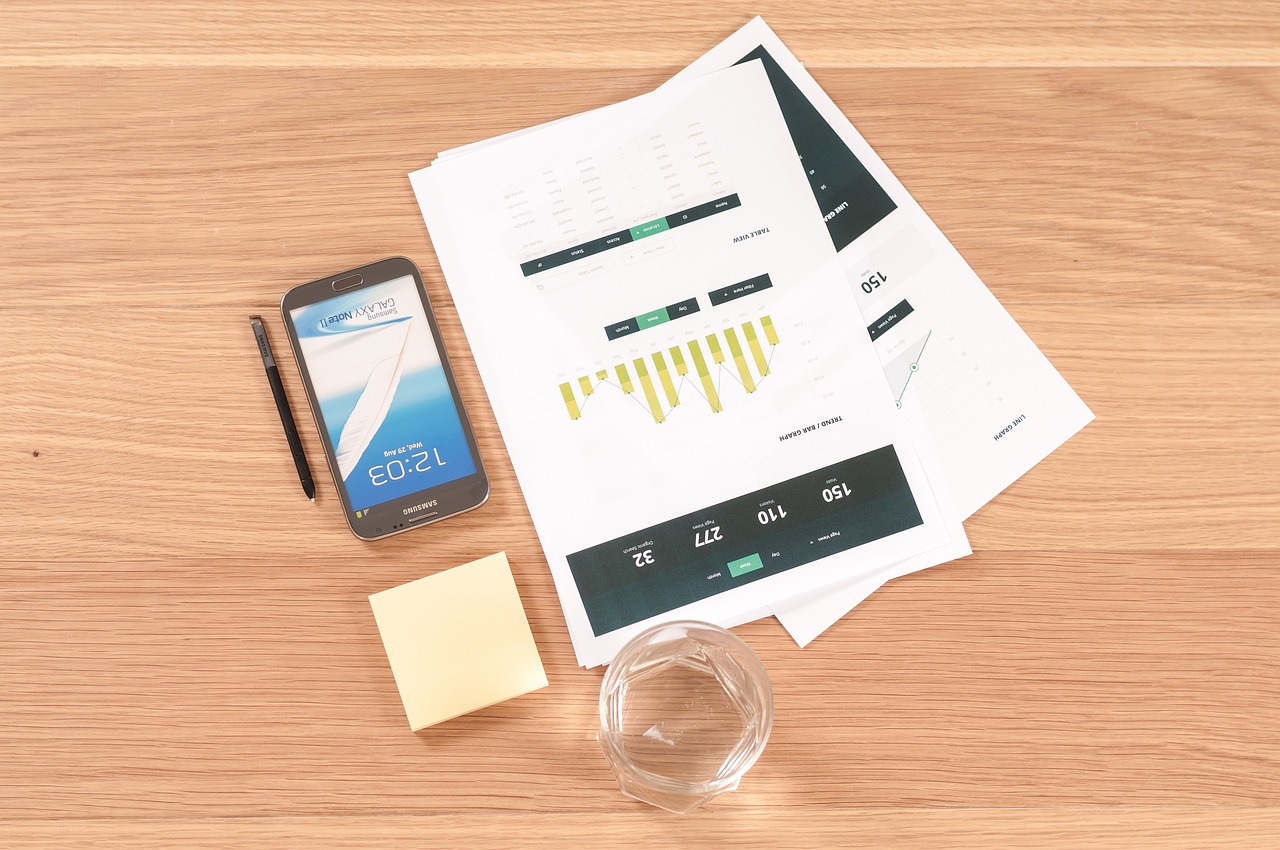 A desk with charts, a phone and a notepad